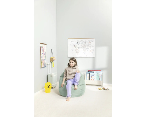 Ljust barnrum med flicka på sittsäck, världskarta, barnbokhylla och leksaker