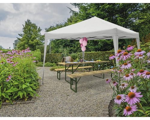 Scen med ett lusthus, en picknickbordsuppsättning och blommor i trädgården