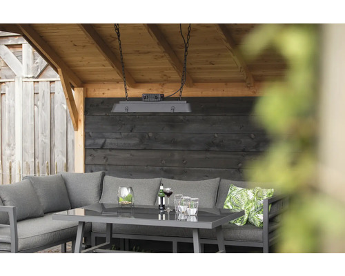 Trädgårdslounge med bord, hörnsoffa, prydnadskuddar och hängande lampa under ett träskydd