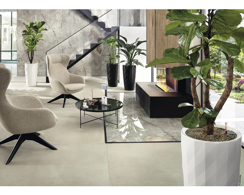 Modern interiör med fåtöljer, bord, växter och öppen spis.