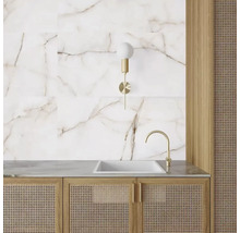 Tvättställ i badrum med marmorplattor, vägglampa och rottingkorgsmöbler