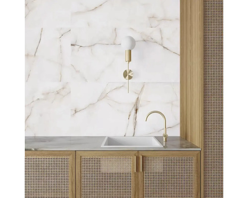 Tvättställ i badrum med marmorplattor, vägglampa och rottingkorgsmöbler