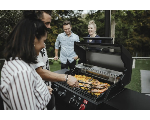 Grupp människor grillar räkor på en gasolgrill utomhus