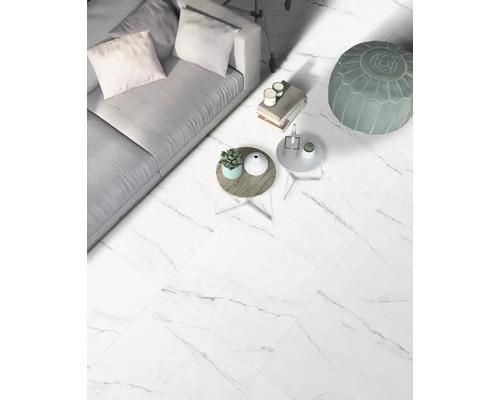 Vardagsrum med soffa, bord och golvplattor i marmorlook.