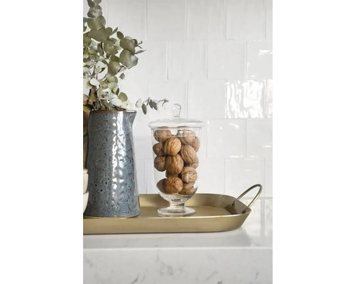 Dekorativ arrangemang med kanna, eukalyptus, glasbehållare och valnötter på en gyllene bricka