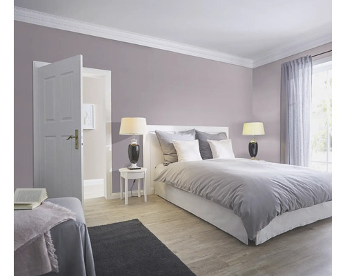 Sovrum med säng, sängbord, lampor och öppen dörr