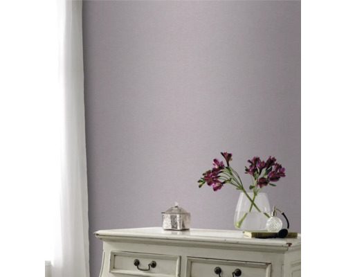 Dekorativt rum med mönstrad tapet på väggen, byrå, blomvas och gardin vid fönstret.