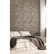Sovrum med tapet i stenlook, säng, sängbord och lampa.