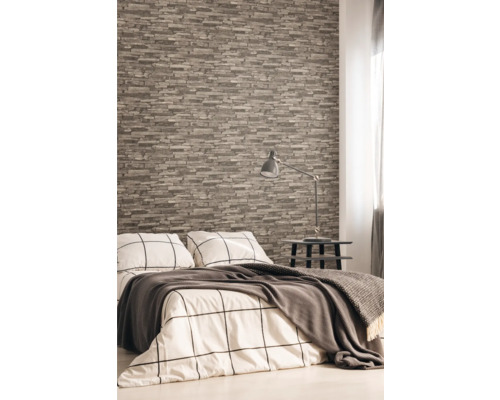 Sovrum med tapet i stenlook, säng, sängbord och lampa.