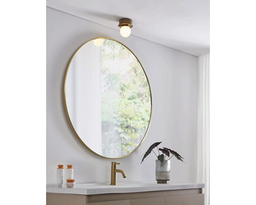 Modernt badrum med rund spegel, tvättställsblandare och taklampa