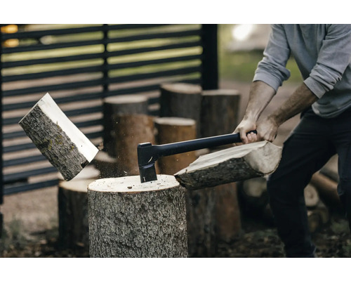 Man hugger ved med yxa på en huggkubbe