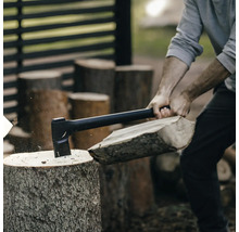 En person hugger ved med en yxa.