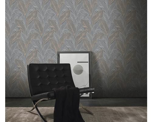 Ett vardagsrum med en grå tapet med bladmönster, en svart läderfåtölj och en inramad bild.