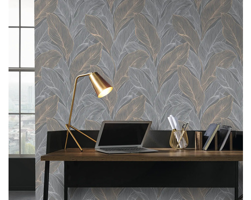 Scen med ett skrivbord, en lampa och en grå tapet med bladmönster