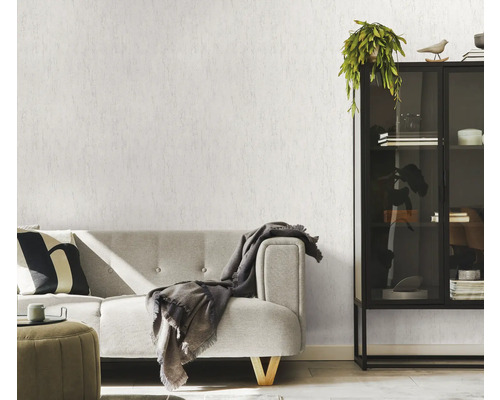 Vardagsrum med soffa, skåp och strukturtapet.