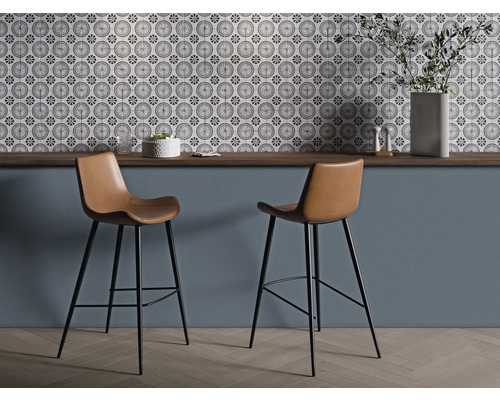 Två barstolar med bruna sitsar och svarta ramar framför en vägg med mönstrade plattor.