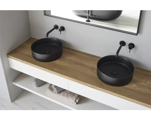 Badrum med två runda tvättställsskålar, armaturer och tvättställsskåp