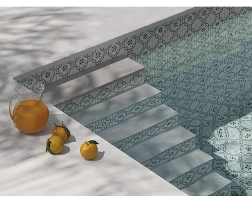 Pool med trappa, kakelmönster och en kanna apelsinjuice