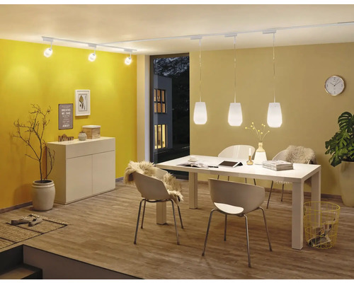 Matsal med matbord, stolar, skänk, takspotlights och pendellampor.