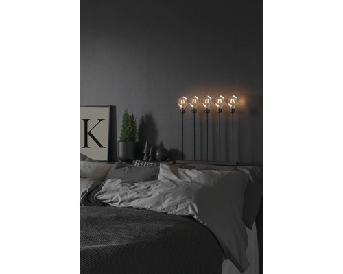 Dekorativt sovrum med säng, sänglampa med fem glödlampor, krukväxt och bild