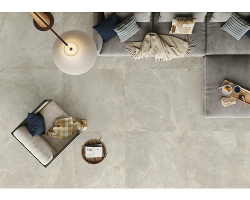 Ljus plattor med marmorlook i ett vardagsrum med soffa, fåtölj och lampa uppifrån