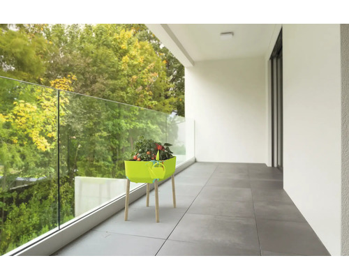 Balkongscen med ett planteringsbord med grönsaker och en vattenkanna