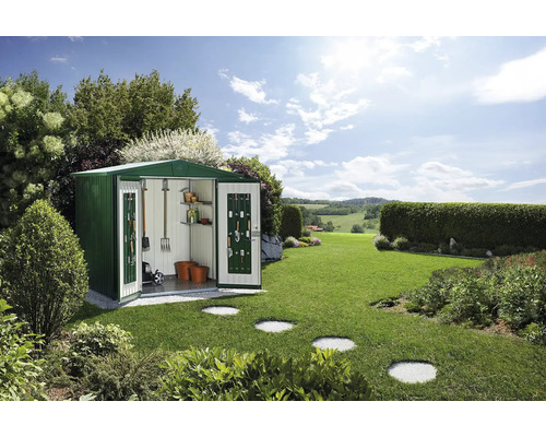 Trädgårdsskjul i metall med öppna dörrar och trädgårdsredskap i grön utomhusmiljö