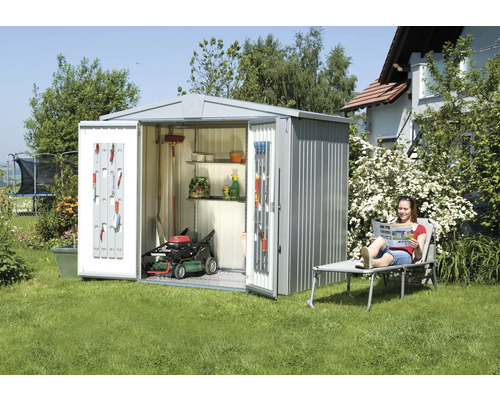 Metallförråd med öppna dörrar, gräsklippare och trädgårdsredskap i trädgården.