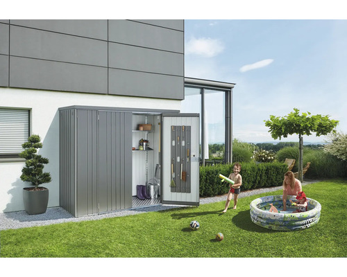Trädgårdsscen med ett verktygsskåp i metall som står mot en byggnad där verktyg förvaras. Barn leker i en uppblåsbar pool.