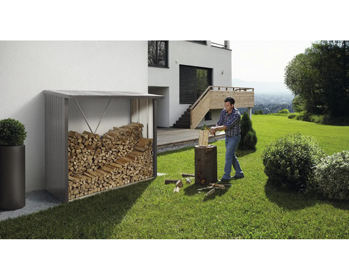 Övertäckt vedförvaring med ved bredvid en man som hugger ved