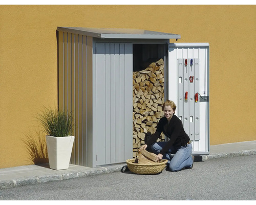 Kvinna fyller vedbod med ved