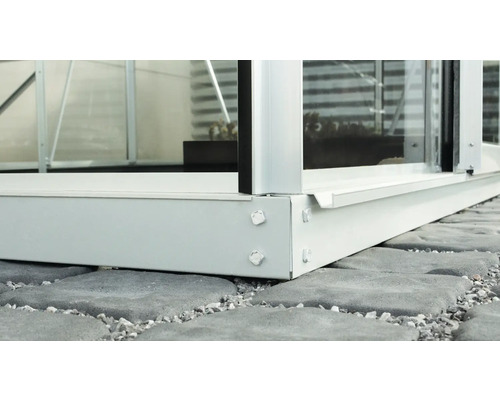 Detaljbild av en aluminiumväxthusbas på stenplattor.