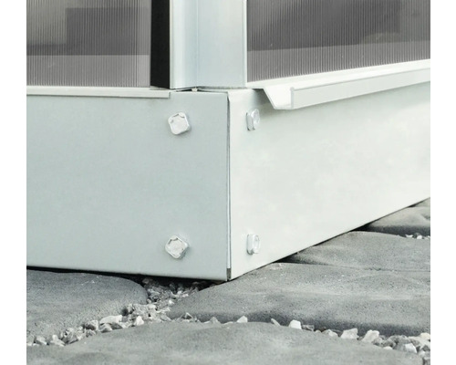 Detaljvy av en växthusgrund av metall med skruvar på stengolv