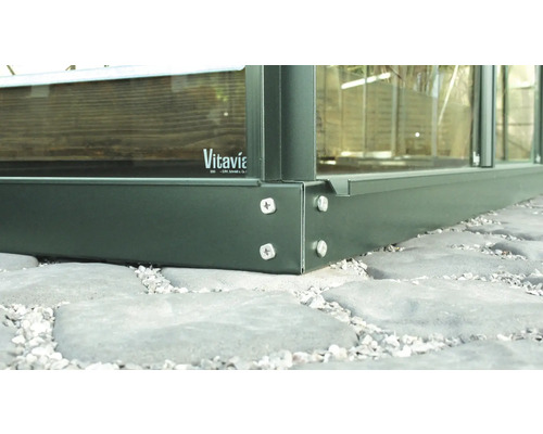 Detaljvy av ett växthus i metall och glas med Vitavia logotyp.