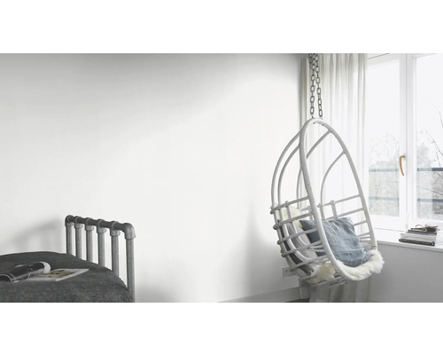 Ljust rum med säng och hängande rottingfåtölj vid fönstret