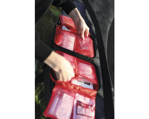 Öppen första hjälpen-väska med rött nätmaterial och olika medicinska artiklar