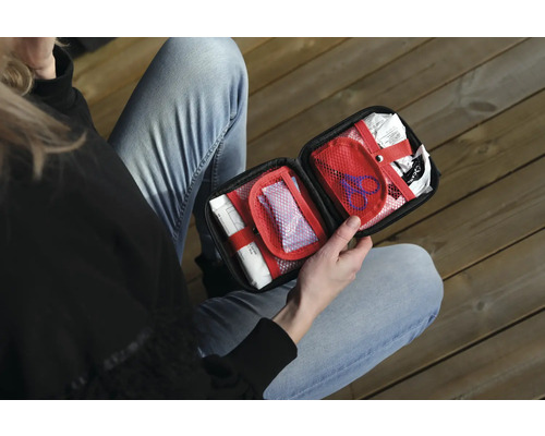 Person håller en öppen första hjälpen-låda med förbandsmaterial.