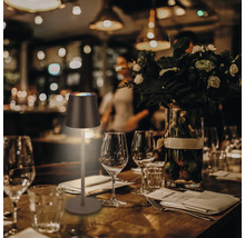 Bordsscen med en LED-bordslampa på ett dukat träbord med glas och bestick