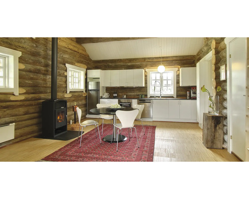 Ljust kök i timmerstuga stil med matbord, vedspis och matta