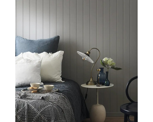 Sovrum med säng, sängbord och lampa framför en vägg med paneler