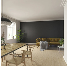 Ljust vardagsrum med trägolv, matbord, stolar och soffa framför en mörk vägg