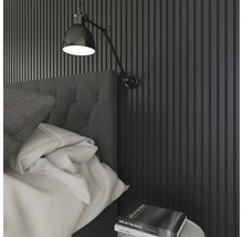 Sovrum med väggpaneler, sänglampa och bok