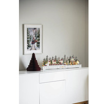 Dekorativ julscen med upplyst vinterlandskap, pappersträd och tågbild på ett vitt skåp