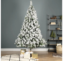 Dekorerad, snötäckt julgran med presenter i vardagsrummet.