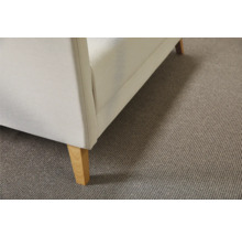Detaljvy av ett beige heltäckningsmatta under en soffa med träben