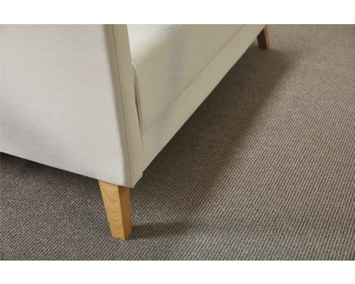 Detaljvy av ett beige heltäckningsmatta under en soffa med träben