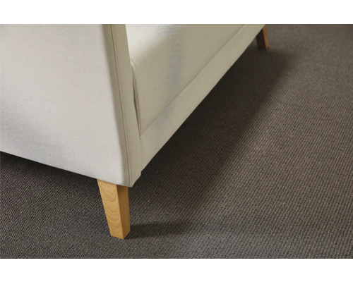 Detaljvy av en soffa med ljus klädsel och träben på en matta