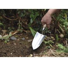 Trädgårdsmästare planterar med en planteringsspade i trädgården.