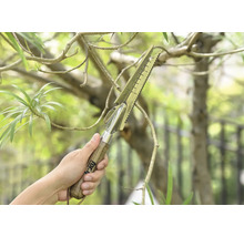 En hand håller ett multifunktionellt trädgårdsredskap med trähandtag