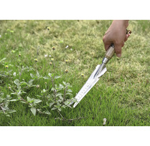 Närbild av en hand som håller en ogrässticka i gräset